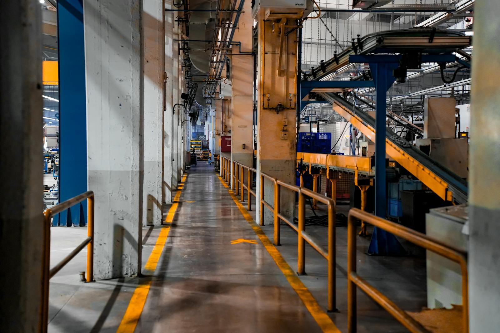 Industrial factory floor with conveyor belt — legacy systems running while modernisation proceeds.